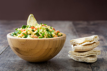 Tabbouleh salad with couscous in wooden bowl on rustic table

