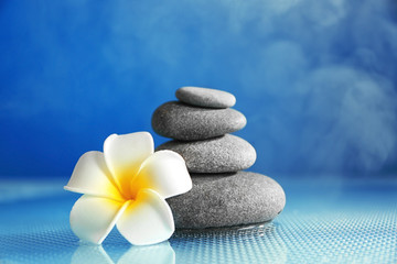 Fototapeta na wymiar Spa stones with plumeria flower on blue background