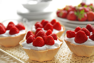 Tasty cakes with strawberries on tray
