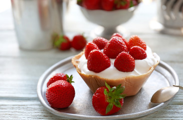 Tasty cake with strawberries in silver plate on wooden background