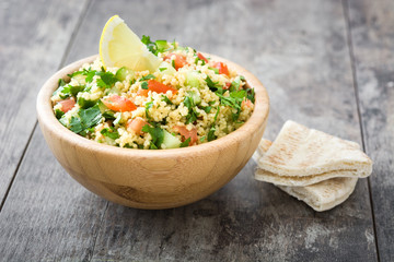 Tabbouleh salad with couscous in wooden bowl on rustic table


