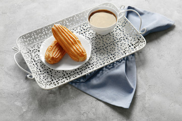 Delicious eclairs and cup of coffee on table