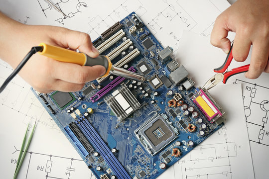 Man using soldering tool for motherboard repair, close up
