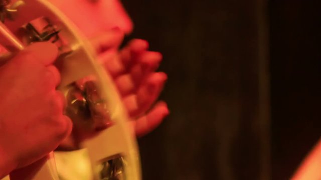 Closeup Hands Play Tambourine in Night Bar under Flashes