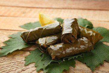 Stuffed delicious Dolma with lemon on vine leaf and wooden background