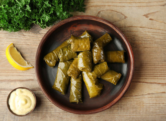 Plate with tasty stuffed Dolma and sauce on wooden table