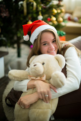 Smiling girl hugs teddy bear in christmas eve