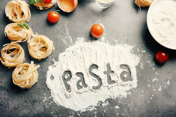 Word PASTA made with flour on kitchen table