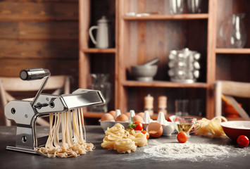 Products, tagliatelle and pasta machine on kitchen table
