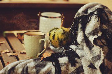 cozy autumn morning at country house, cup of tea and warm blanket on wooden table. Still life details