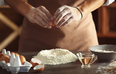 Man preparing dough on kitchen table, close up view