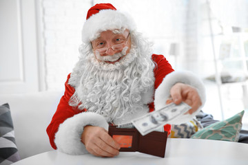 Santa Claus holding wallet with money and credit card at home