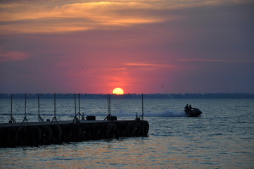 Fototapeta premium Sunset and moving scooter near the coast