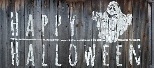 Happy Halloween banner. Greeting lettering on the old fence. Horizontal banner with a very cute funny ghost. Cracked paint and old fence texture. Realistic 3d illustration. Design template. 