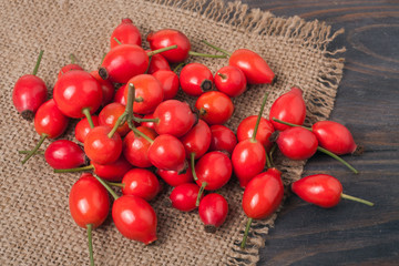 fresh rose hips on a wooden table with sacking