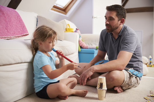 Father Watches Daughter Playing Whistle In Playroom