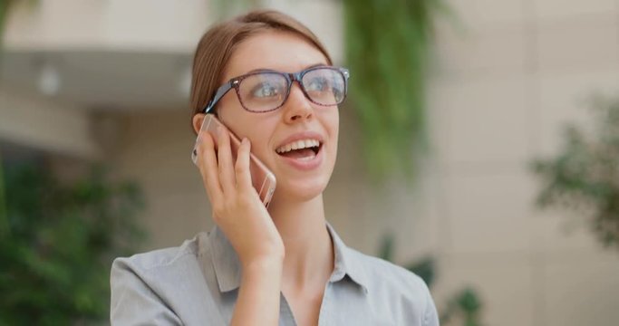 young and attractive business woman talking on the phone walking along the bank