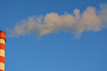 Naklejka na ściany i meble smoke from the striped tube heat and power plant against the blue sky, heat, pollution