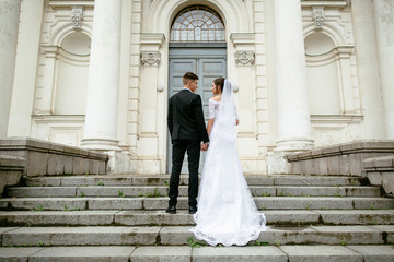 Wedding day. Wedding couple, bride and groom holding hands and going up the stairs of the castle.