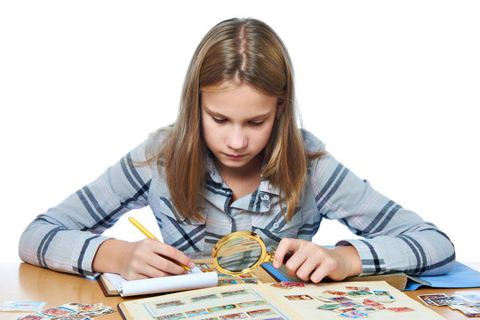 Teen girl with magnifier looks his stamp collection isolated
