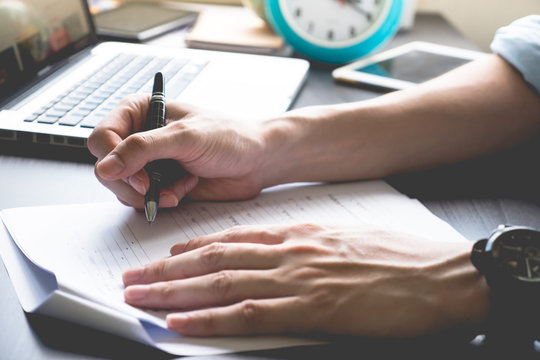 Close up of male hands writing on paper on his office desk.