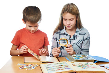Girl and boy with magnifier looking his stamp collection isolate