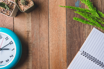 Top view of Blank notebook with clock,paddy rice and cactus on wooden table.