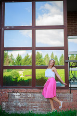 Portrait of a beautiful young girl on the background of the Windows in the Park skirt