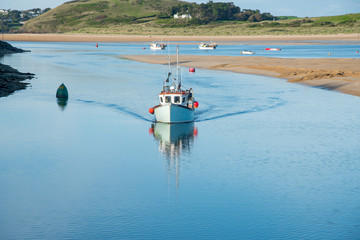 Fototapeta na wymiar Fishing boat arrives in the port of Padstow at the Camel estuary in north Cornwall.