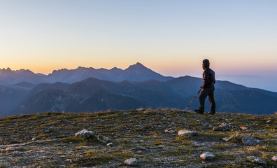 Obraz premium Tourist with trekking poles admire the sunrise.