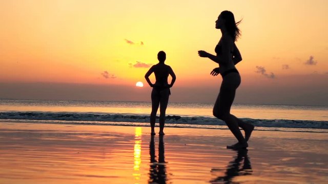 Pretty, young woman in bikini running on the beach during sunset, super slow motion
