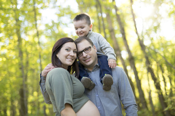 Happy pregnant family having fun in autumn nature