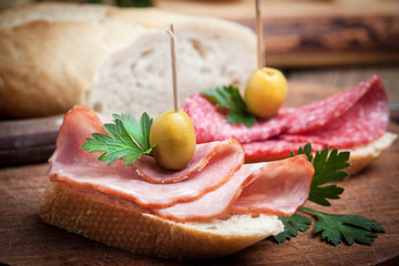 Tapas with sliced sausage, salami, olives and parsley.