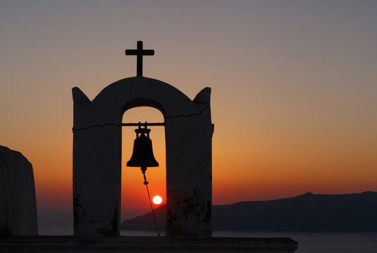 view on sunset through bell tower of Agios Minas church on Santorini