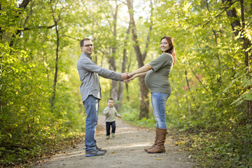 Obraz premium Beautiful pregnant couple relaxing outside in the park.