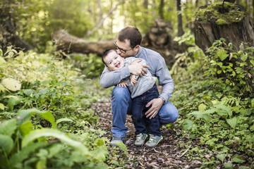 Little boy and his father on grass in autumn forest