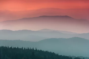 Foto op Canvas Landscape with colorful layers of mountains and haze  hills covered by forest. The effect of color tinting. Mountains silhouettes. © vovik_mar