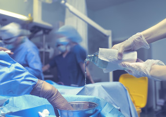 Assistant pours sterile solution during surgery