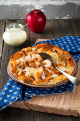 Bread pudding breakfast casserole with apples and vanilla sauce on the old wooden background. Selective focus.