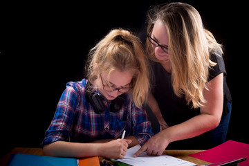une femme adulte aide une adolescente à faire ses devoirs scolaires