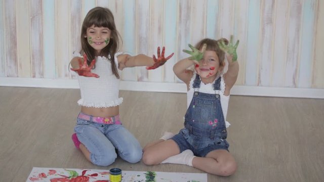 two little girls draw with finger paints