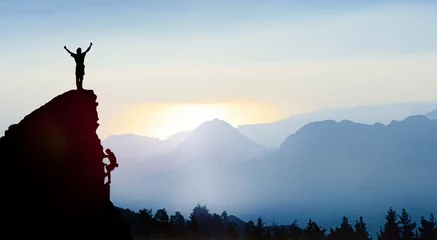 Gordijnen Klimmer op een piek in de bergen bij zonsopgang © Visions-AD