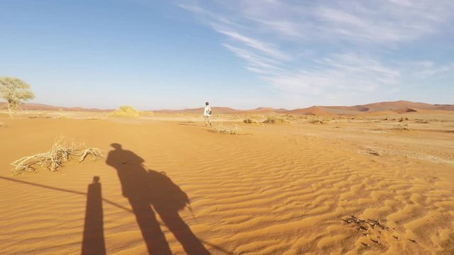 Tourist walking in the majestic Namib desert, Sossusvlei, Namib Naukluft National Park, main visitor attraction and travel destination in Namibia. Adventures in Africa.