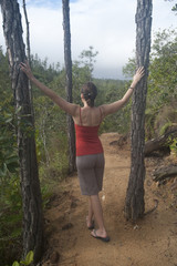 Woman standing between two trees at Mountain Pine Ridge Reserve in Belize