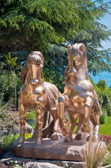 Fototapeta na wymiar A pair of golden horses statue adorns an alley in the park.