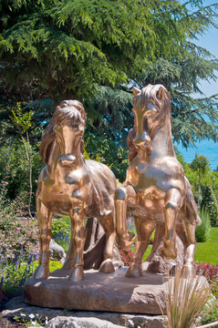 A pair of golden horses statue adorns an alley in the park.