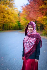 Muslim woman in Canada during autumn with colorful maple leaf as background 