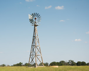 Windpump with a watertank at the base of it, with blades turning in the high winds