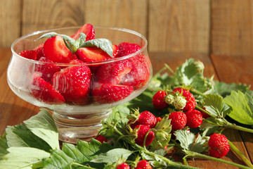 strawberries in transparent bowl and bunches with leaves