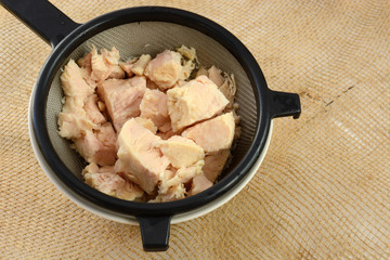 Rinsed canned chicken in strainer inside white bowl